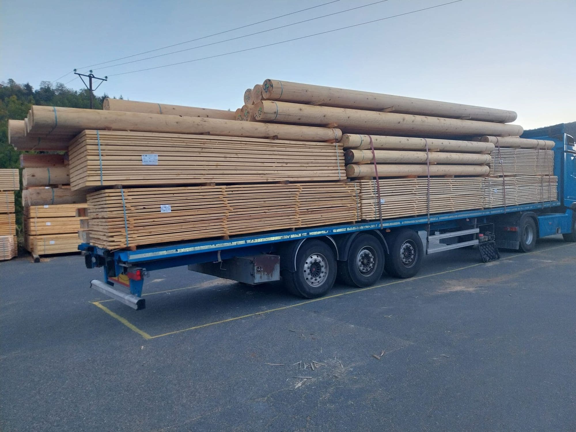 Semi-remorque chargée de bois sciés et de bois ronds au départ de la scierie